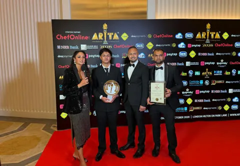 Spice Merchants representatives holding a trophy and certificate during a red-carpet interview at ARTA 2026